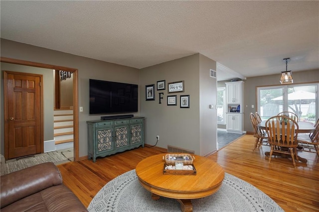 315 Goodrich Dr, Warrensburg, MO 64093 - living room featuring light wood-style flooring, a textured ceiling, and stairway