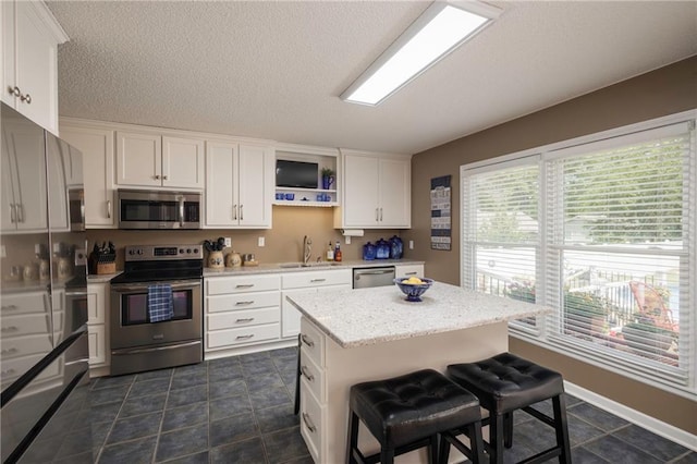 315 Goodrich Dr, Warrensburg, MO 64093 - kitchen with appliances with stainless steel finishes, white cabinets, a kitchen bar, open shelves, and a kitchen island