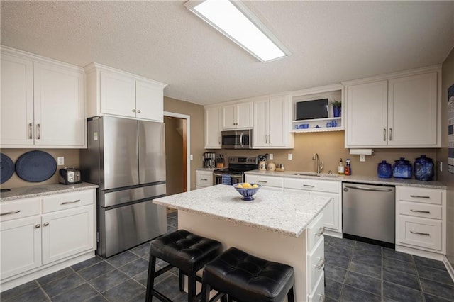315 Goodrich Dr, Warrensburg, MO 64093 - kitchen featuring appliances with stainless steel finishes, white cabinets, dark tile patterned flooring, a center island, and a breakfast bar