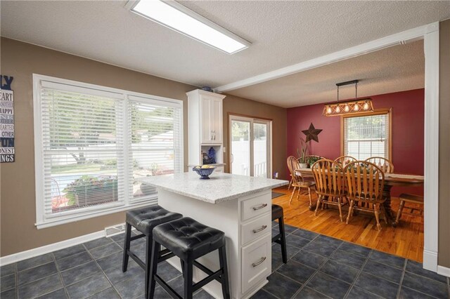 315 Goodrich Dr, Warrensburg, MO 64093 - kitchen featuring a breakfast bar, white cabinetry, healthy amount of natural light, and a textured ceiling