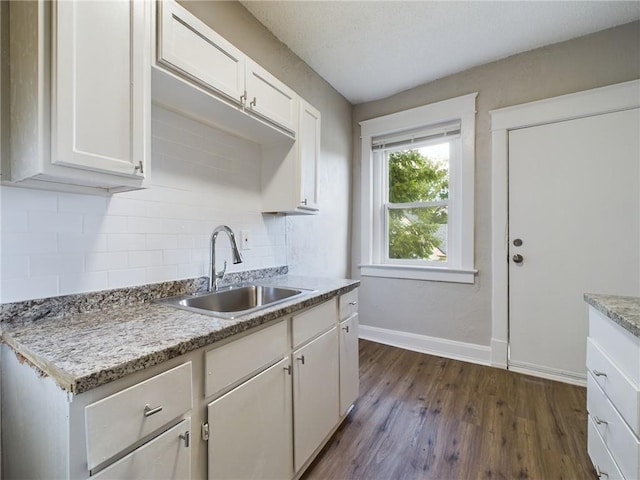 2416 E 22nd St, Kansas City, MO 64127 - kitchen with dark wood finished floors, decorative backsplash, and white cabinets