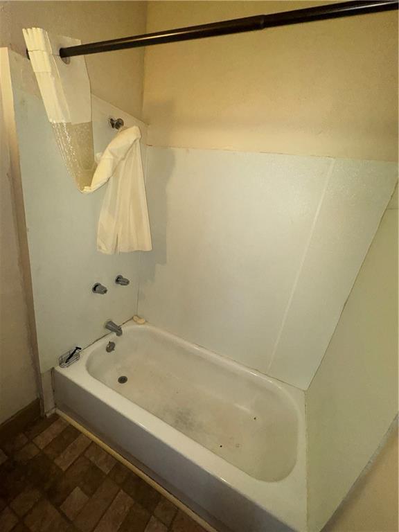 2416 E 22nd St, Kansas City, MO 64127 - bathroom featuring shower / tub combination and brick patterned floors