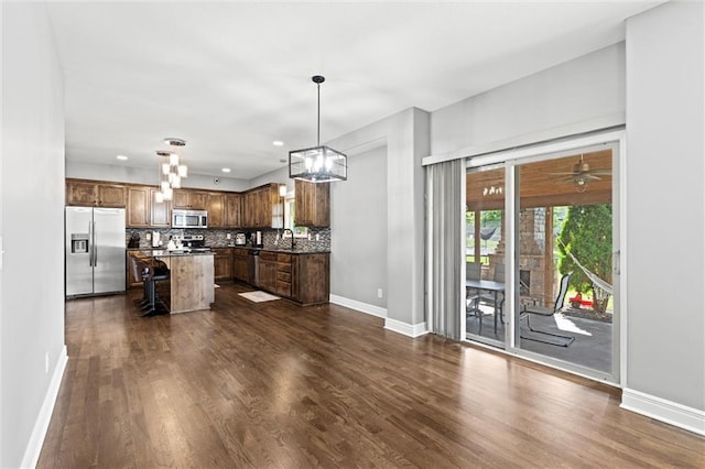 514 NE Viewpark Dr, Lees Summit, MO 64086 - kitchen featuring appliances with stainless steel finishes, dark wood-type flooring, decorative backsplash, a kitchen island, and recessed lighting