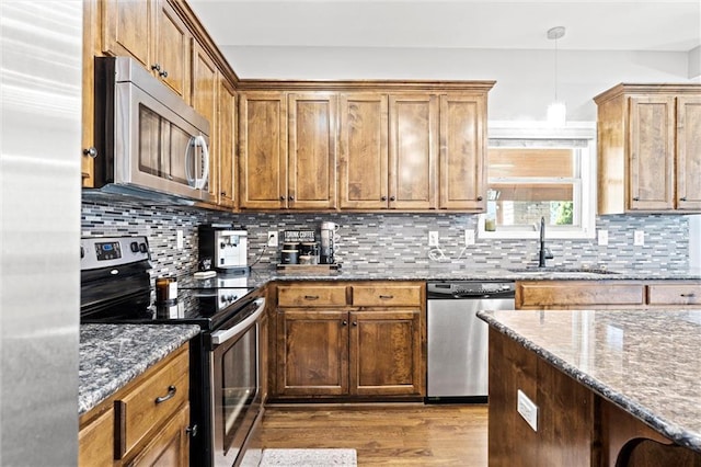 514 NE Viewpark Dr, Lees Summit, MO 64086 - kitchen with appliances with stainless steel finishes, dark wood-style flooring, dark stone counters, and decorative backsplash