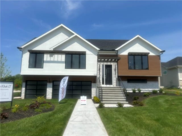 4313 SE Adams Dr, Blue Springs, MO 64014 - view of front facade with stucco siding, an attached garage, and a front yard