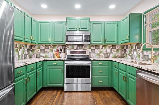1521 W 22nd St, Lawrence, KS 66046 - kitchen with appliances with stainless steel finishes, dark wood-style flooring, decorative backsplash, and light stone counters