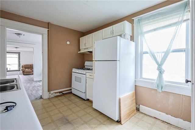 2512 Jules St, Saint Joseph, MO 64501 - kitchen with white appliances, under cabinet range hood, light floors, light countertops, and white cabinetry