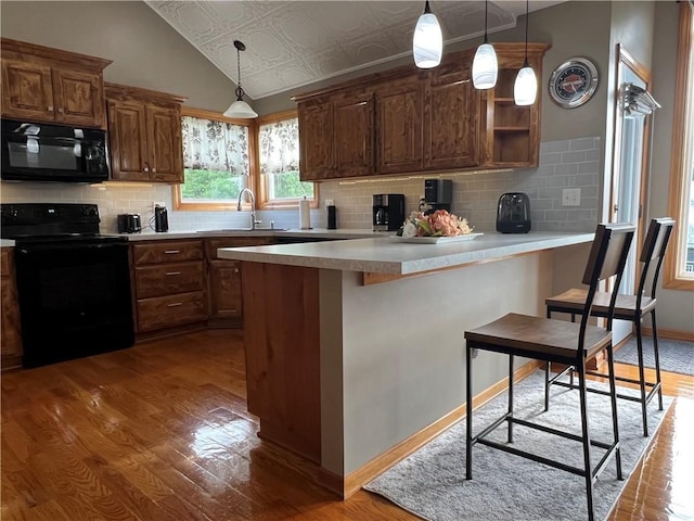 938 S 17th St, Leavenworth, KS 66048 - kitchen with black appliances, wood finished floors, a peninsula, an ornate ceiling, and tasteful backsplash