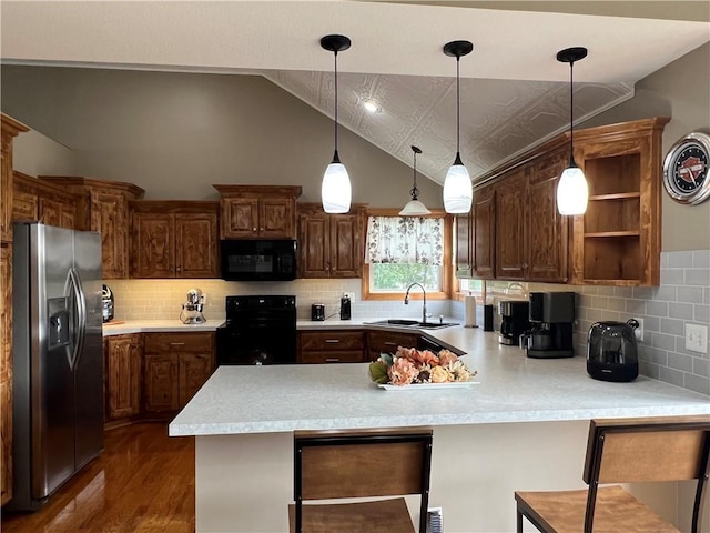 938 S 17th St, Leavenworth, KS 66048 - kitchen with black appliances, a peninsula, vaulted ceiling, light countertops, and dark wood finished floors