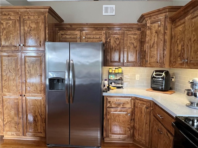 938 S 17th St, Leavenworth, KS 66048 - kitchen with stainless steel fridge, backsplash, light countertops, black range with electric cooktop, and brown cabinetry
