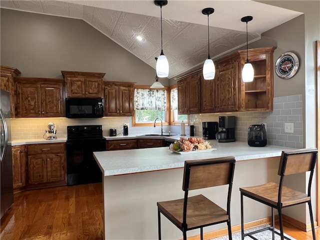 938 S 17th St, Leavenworth, KS 66048 - kitchen with black appliances, a peninsula, dark wood-style floors, light countertops, and lofted ceiling