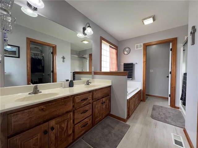 938 S 17th St, Leavenworth, KS 66048 - full bath with wood finished floors, double vanity, a bath, a walk in closet, and a shower stall