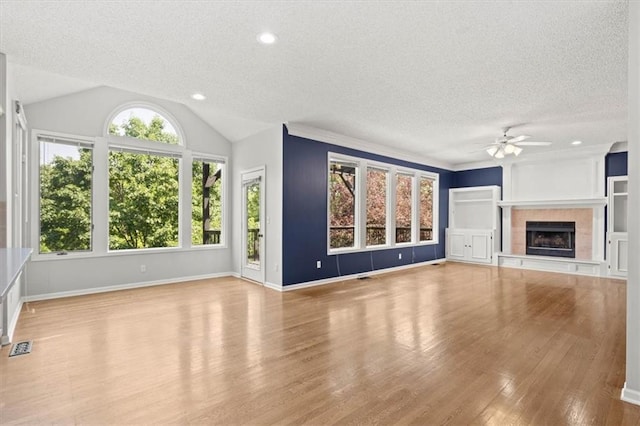 18970 W 115th Ter, Olathe, KS 66061 - unfurnished living room with a textured ceiling, a ceiling fan, wood finished floors, a tile fireplace, and vaulted ceiling