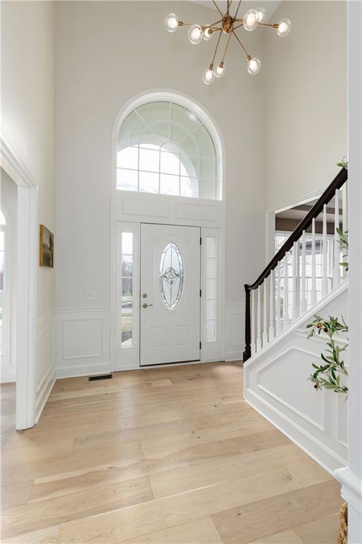 14600 Reinhardt Ln, Leawood, KS 66224 - foyer with a decorative wall, a high ceiling, a chandelier, stairway, and light wood finished floors
