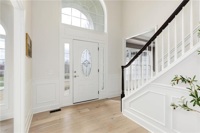 14600 Reinhardt Ln, Leawood, KS 66224 - entrance foyer featuring a decorative wall, healthy amount of natural light, stairway, a wainscoted wall, and a high ceiling
