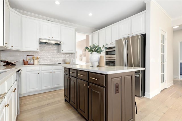 14600 Reinhardt Ln, Leawood, KS 66224 - kitchen with crown molding, white cabinetry, stainless steel appliances, light wood-type flooring, and under cabinet range hood