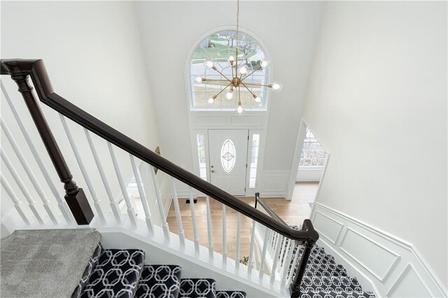 14600 Reinhardt Ln, Leawood, KS 66224 - stairway featuring a towering ceiling, a decorative wall, a wainscoted wall, and a chandelier