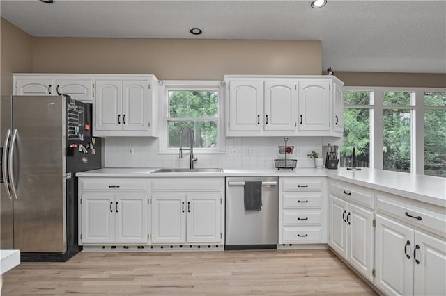 5303 Hallet St, Shawnee, KS 66216 - kitchen with appliances with stainless steel finishes, backsplash, white cabinetry, light wood finished floors, and light countertops