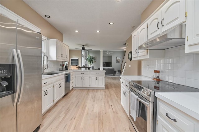 5303 Hallet St, Shawnee, KS 66216 - kitchen with appliances with stainless steel finishes, under cabinet range hood, a ceiling fan, a peninsula, and light wood-type flooring