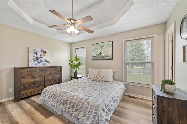 103 Bridgeport Dr, Smithville, MO 64089 - bedroom featuring a tray ceiling, light wood-style floors, multiple windows, a textured ceiling, and a ceiling fan