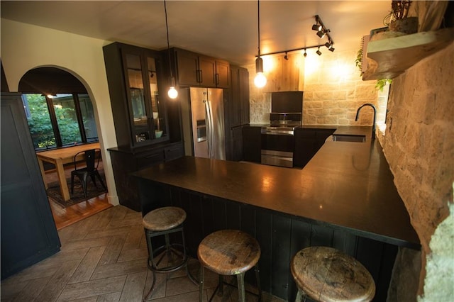 11001 S Perdue Rd, Grain Valley, MO 64029 - kitchen featuring stainless steel appliances, a peninsula, track lighting, glass insert cabinets, and a kitchen bar
