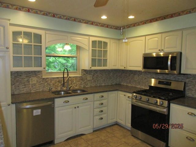 19005 E 18th Ter N, Independence, MO 64058 - kitchen with stainless steel appliances, a sink, dark countertops, decorative backsplash, and glass insert cabinets