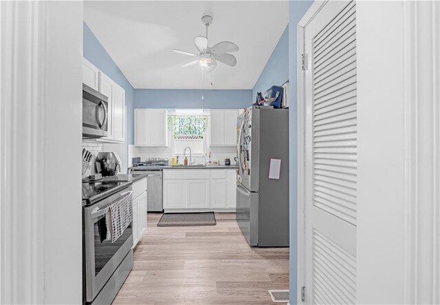 1112 Anderson St, Warrensburg, MO 64093 - kitchen with appliances with stainless steel finishes, a ceiling fan, vaulted ceiling, white cabinets, and light wood-type flooring