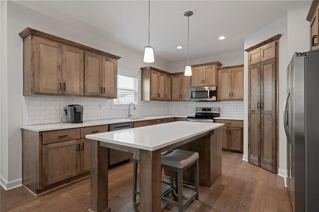24840 W 178th Ct, Gardner, KS 66030 - kitchen with appliances with stainless steel finishes, a kitchen bar, dark wood-type flooring, tasteful backsplash, and a kitchen island