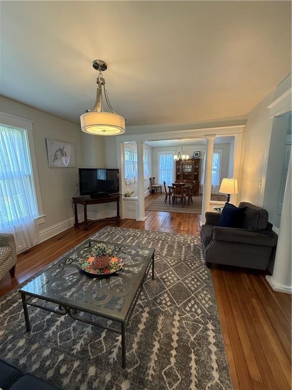 928 S 6th St, Atchison, KS 66002 - living area featuring decorative columns, wood finished floors, and a chandelier