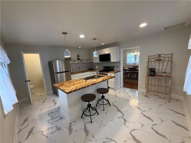 928 S 6th St, Atchison, KS 66002 - kitchen featuring butcher block countertops, stainless steel appliances, recessed lighting, white cabinets, and a kitchen island with sink