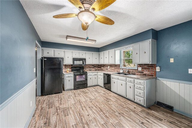 308 E Meadow St, Smithville, MO 64089 - kitchen featuring black appliances, a wainscoted wall, a textured ceiling, light wood-style flooring, and white cabinetry