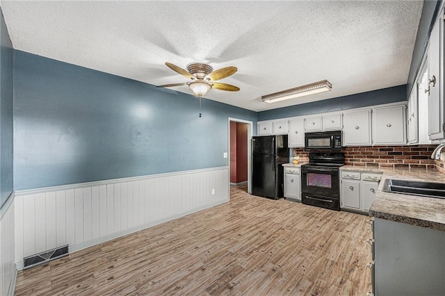 308 E Meadow St, Smithville, MO 64089 - kitchen with black appliances, ceiling fan, wainscoting, light wood-style flooring, and a textured ceiling