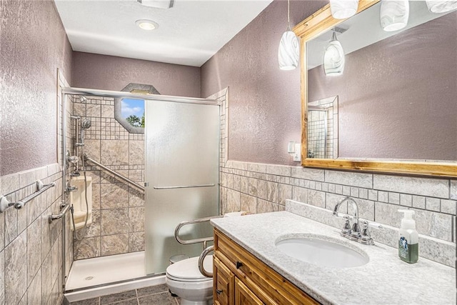 308 E Meadow St, Smithville, MO 64089 - bathroom with tile walls, a textured wall, vanity, tile patterned floors, and a stall shower