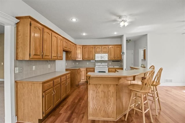 1111 SW 13th St, Oak Grove, MO 64075 - kitchen with white appliances, wood finished floors, tasteful backsplash, a kitchen island with sink, and recessed lighting