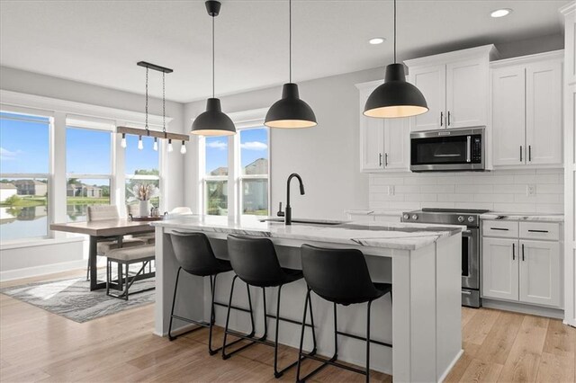 1104 SW Magnolia Cir, Oak Grove, MO 64075 - kitchen with appliances with stainless steel finishes, a center island with sink, backsplash, recessed lighting, and light stone countertops