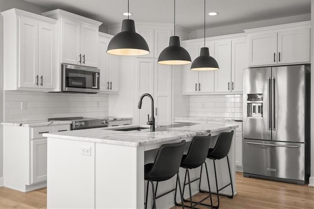 1104 SW Magnolia Cir, Oak Grove, MO 64075 - kitchen with appliances with stainless steel finishes, recessed lighting, white cabinetry, light wood-style flooring, and light stone countertops