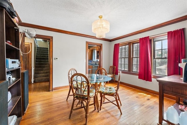 402 Fifth St, Smithville, MO 64089 - dining space with stairs, a textured ceiling, light wood-style flooring, a chandelier, and crown molding