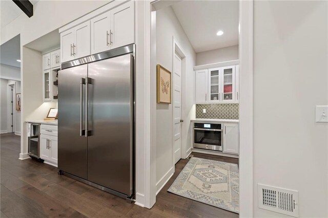 11807 S Kenton St, Olathe, KS 66061 - kitchen featuring stainless steel appliances, dark wood-type flooring, glass insert cabinets, white cabinetry, and beverage cooler