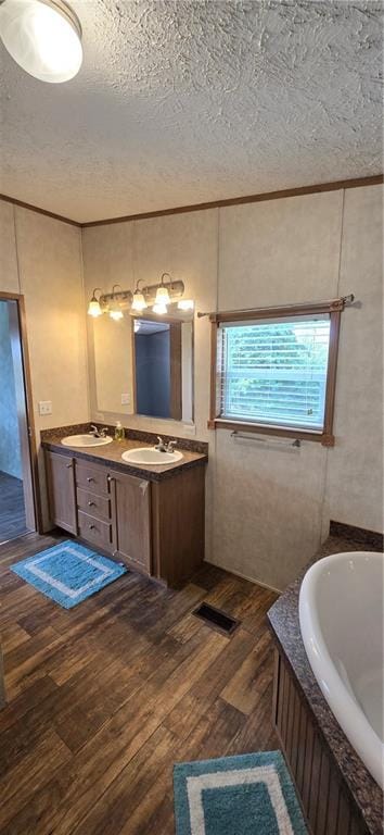 2251 Nemaha Rd, Cummings, KS 66016 - bathroom with a textured ceiling, double vanity, wood-type flooring, a garden tub, and crown molding