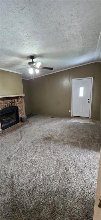 2251 Nemaha Rd, Cummings, KS 66016 - unfurnished living room with a fireplace, a ceiling fan, a textured ceiling, carpet flooring, and ornamental molding