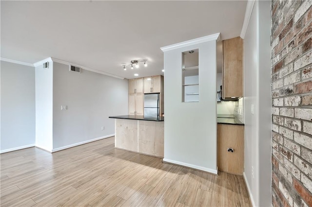 5008 Baltimore Ave Unit 102, Kansas City, MO 64112 - kitchen with stainless steel refrigerator, ornamental molding, dark countertops, light wood-style flooring, and brick wall