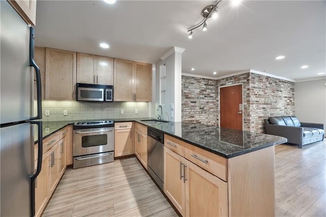 5008 Baltimore Ave Unit 102, Kansas City, MO 64112 - kitchen featuring appliances with stainless steel finishes, light brown cabinets, a peninsula, ornamental molding, and open floor plan