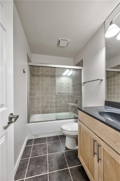 5008 Baltimore Ave Unit 102, Kansas City, MO 64112 - full bath with vanity, tile patterned floors, and shower / bath combination with glass door