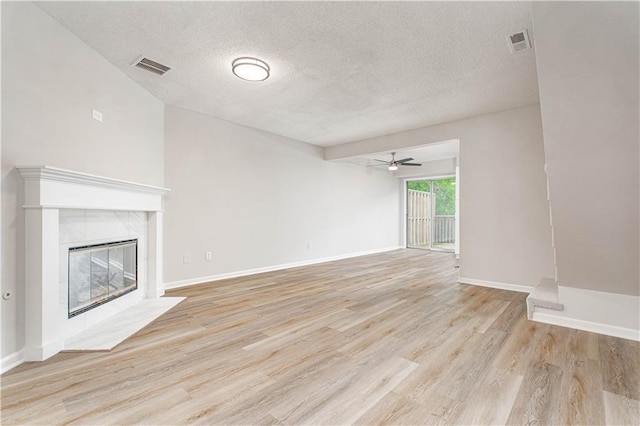 4612 Whispering Winds Dr Unit B, Lees Summit, MO 64064 - unfurnished living room featuring ceiling fan, light wood finished floors, a textured ceiling, and a tile fireplace