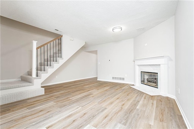 4612 Whispering Winds Dr Unit B, Lees Summit, MO 64064 - unfurnished living room featuring wood finished floors, stairway, a fireplace, and a textured ceiling