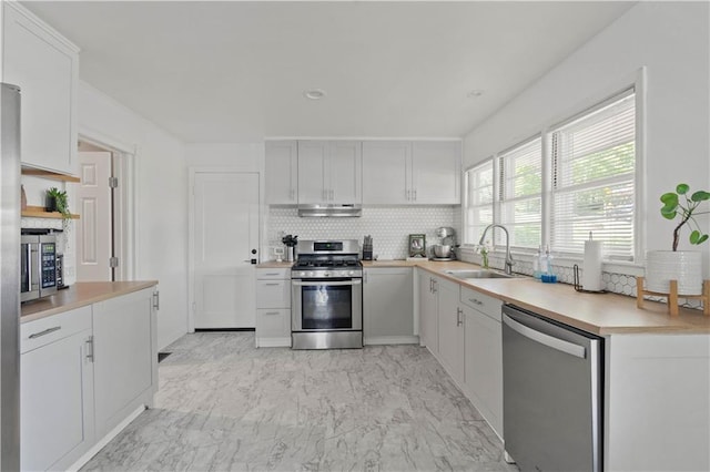 7801 W 55th Ter, Overland Park, KS 66202 - kitchen with appliances with stainless steel finishes, decorative backsplash, light countertops, light marble finish floors, and under cabinet range hood