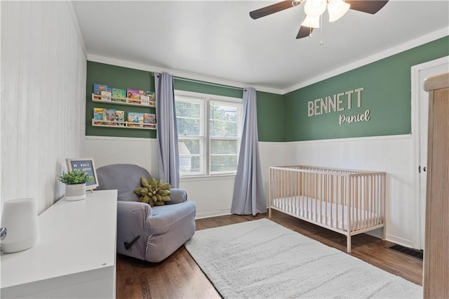 7801 W 55th Ter, Overland Park, KS 66202 - bedroom with wood finished floors, wainscoting, a ceiling fan, a crib, and ornamental molding