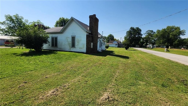 304 N Mckinley St, Weir, KS 66781 - view of home's exterior featuring a chimney, a lawn, and driveway