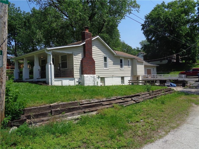 11401 E Scarritt Ave, Sugar Creek, MO 64054 - view of home's exterior with covered porch and a chimney
