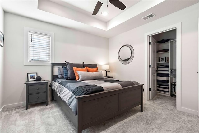 11594 S Zarda Dr, Olathe, KS 66061 - bedroom featuring a walk in closet, light colored carpet, a tray ceiling, a closet, and ceiling fan